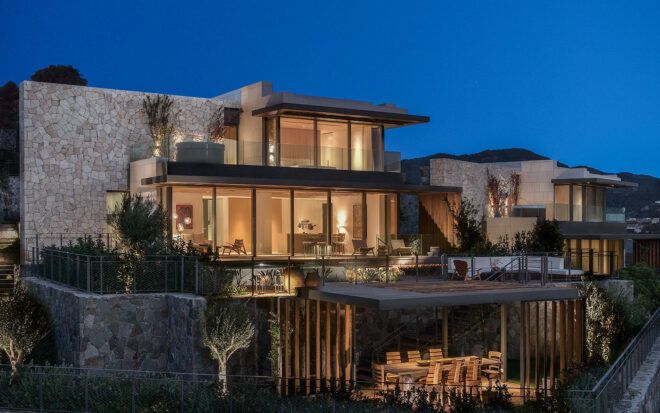 villa with glass walls lit from within at dusk