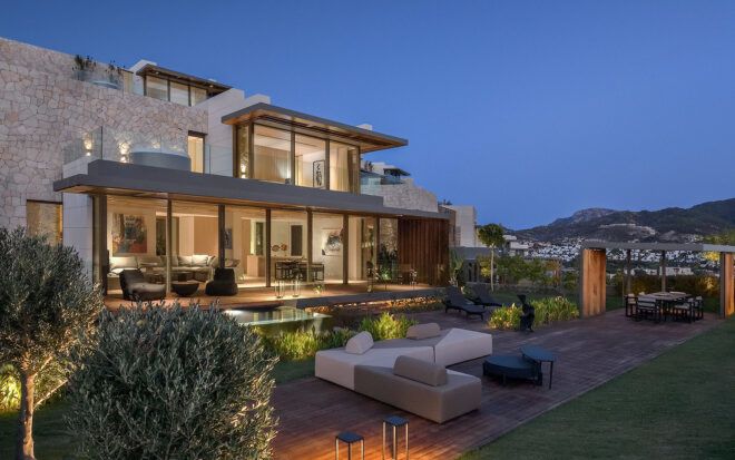 gray and white patio furniture next to villa with glass walls