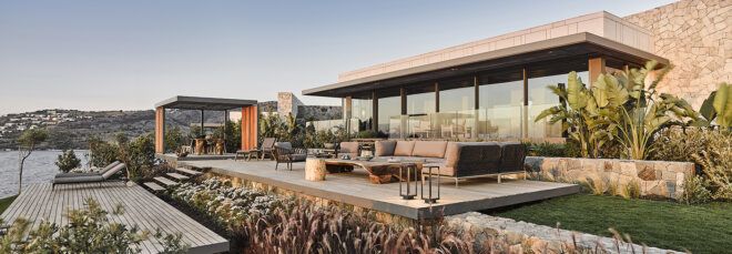 patio with gray sofa next to villa with glass walls