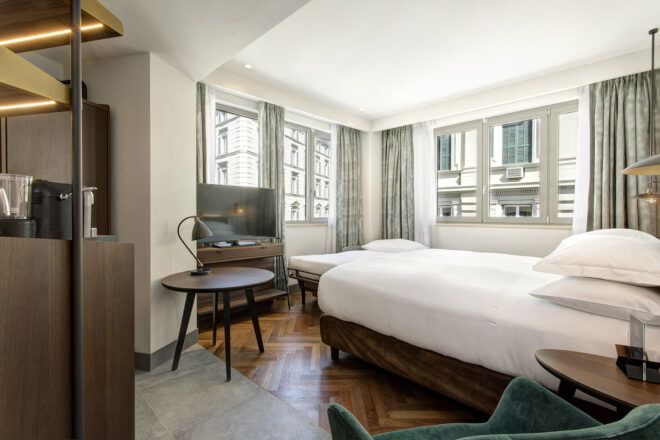 A bedroom with a white bed, white walls and several windows.