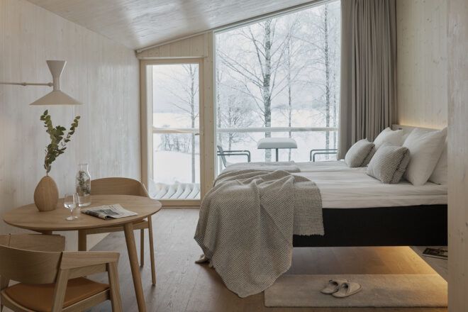 fluffy white bed next to angled wall made of glass