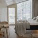 fluffy white bed next to angled wall made of glass