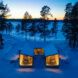 U-shaped cabin covered in snow and lit from within at dusk