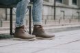 person wearing jeans and brown vegan rain boots