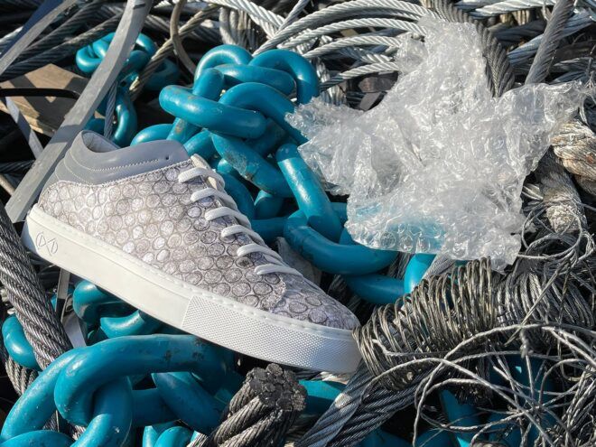 gray vegan shoe next to bubble wrap in a pile of trash