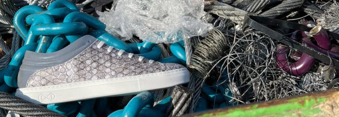 gray vegan shoe next to bubble wrap in a pile of trash