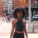 A person in a halter top, standing on the corner of a city street.