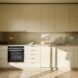 A kitchen with off-white flooring and tile backsplash. The kitchen has white cabinets and a black oven.