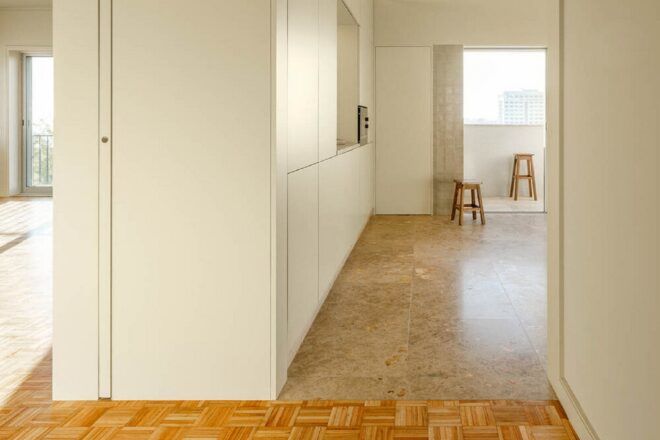 A hallway showing the living room to the left and a kitchen to the right.