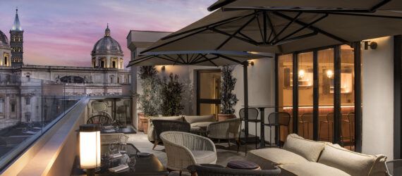 A rooftop bar during the evening, featuring umbrella overhangs covering several seats.