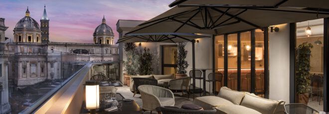 A rooftop bar during the evening, featuring umbrella overhangs covering several seats.