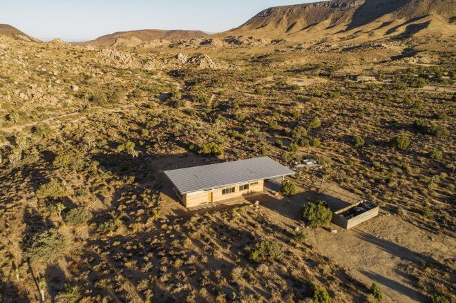 An overhead view of a flat-topped overhanging roof on a house in the middle of a desert.