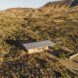 An overhead view of a flat-topped overhanging roof on a house in the middle of a desert.