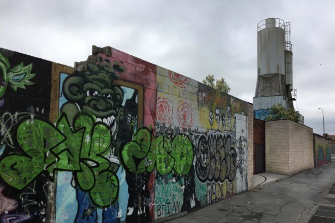 A sideview of a windowless house covered in graffiti.
