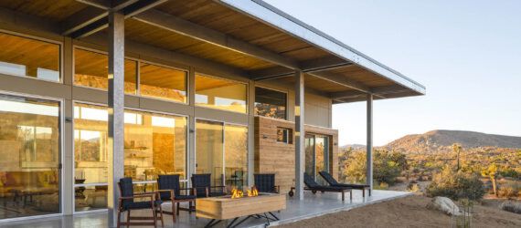 A covered patio connects to floor-to-ceiling windows.