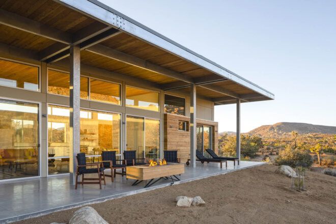 A covered patio connects to floor-to-ceiling windows.