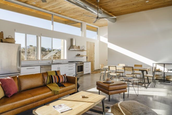 A living room with white walls, a wood ceiling and brown leather furniture.