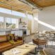 A living room with white walls, a wood ceiling and brown leather furniture.
