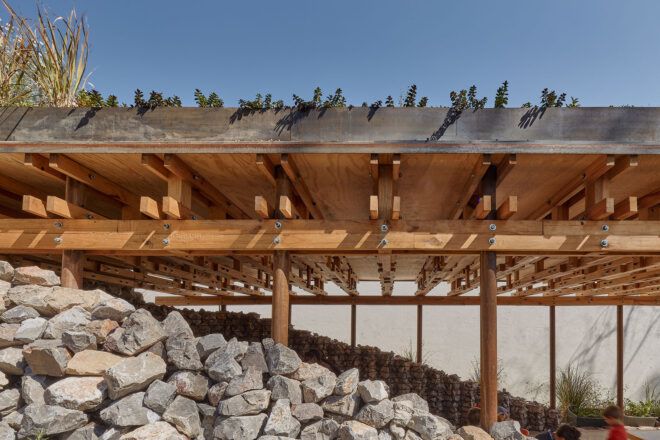 A close-up of a stone wall around a wood pavilion.