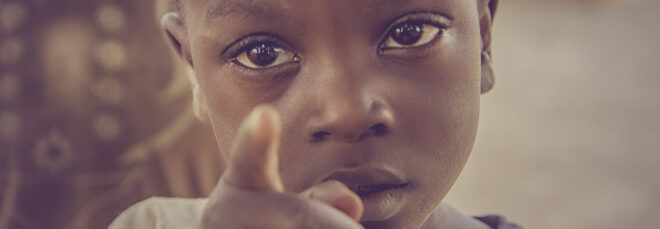 A child looking and pointing at the camera.
