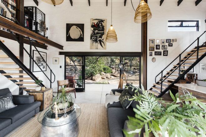 A decorated living room with white walls and dark wood accents. Large sliding glass doors connect the space to the outdoors.