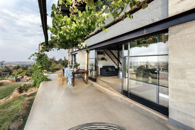 Large sliding glass doors that open onto a bright patio surrounded by greenery.
