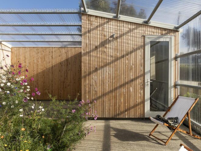 A home with wood cladding and a glass roof cover surrounding a green courtyard.