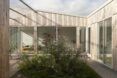 A home with white wood cladding surrounding a green courtyard.