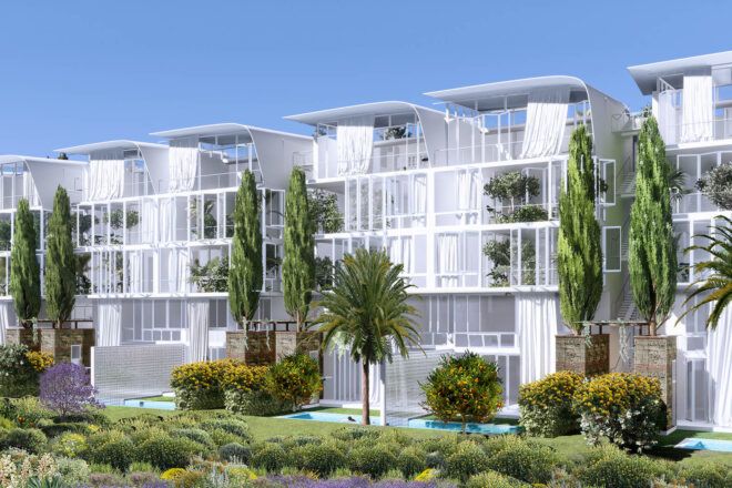 A side angle of white box-like structures surrounded by plants, with pools in front.