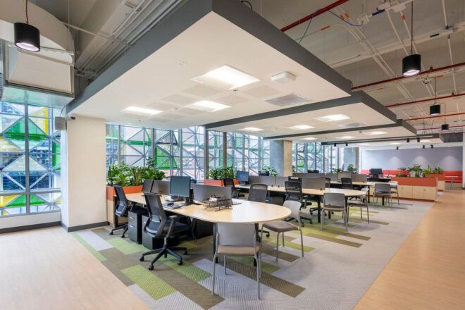 A study room with several oval-shaped tables with computer set-ups surrounded by chairs.