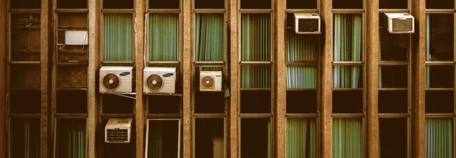 A row of apartment windows with attached AC units.