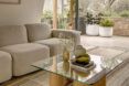 A living room with a glass coffee table in front of an off-white sofa.