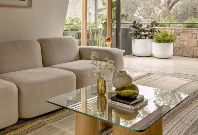 A living room with a glass coffee table in front of an off-white sofa.