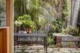 An outdoor patio with an iron table and chair surrounded by greenery.