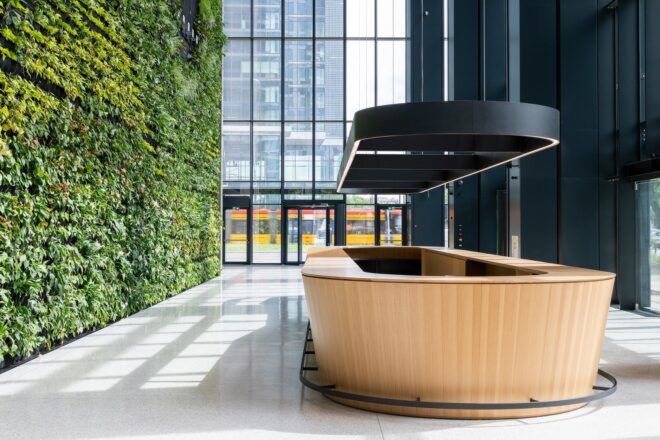 A sideview of an oval-shaped wood desk to the right of a large green wall.