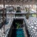 A dappled roof sends a pattern of light and shadow over a covered pool area.