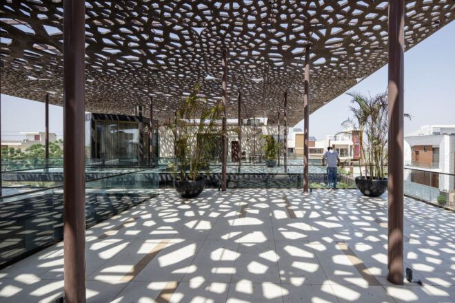 A dappled roof sends a pattern of light and shadow over a covered courtyard.