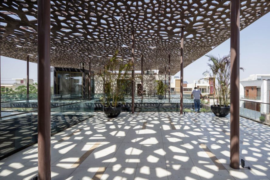 A dappled roof sends a pattern of light and shadow over a covered courtyard.