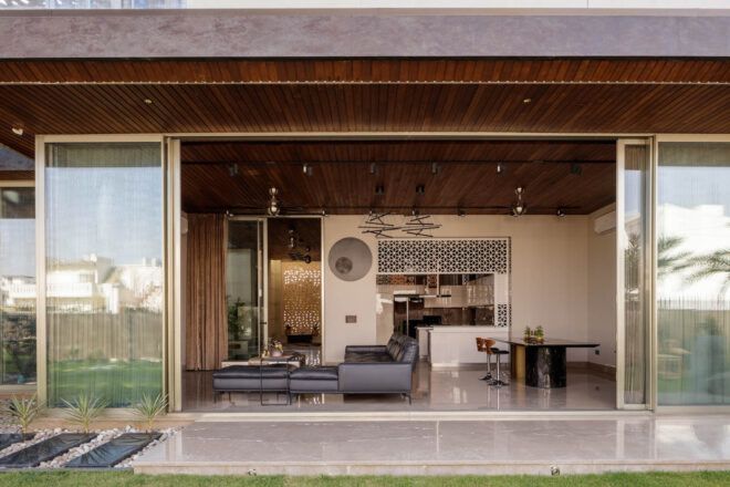 Open sliding glass doors look into a living room area from the yard.