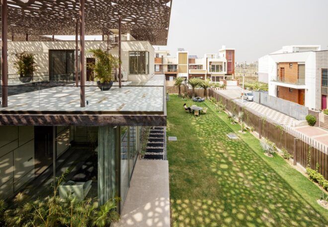 A dappled roof sends a pattern of light and shadow over the side of the home and onto the yard.