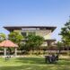 A green yard with a family lounging on it in front of a home with a stone facade and overhanging roof.