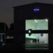 A dark landscape lit up only by a NASA building with a NASA sign on top and a large open factory door looking inside.