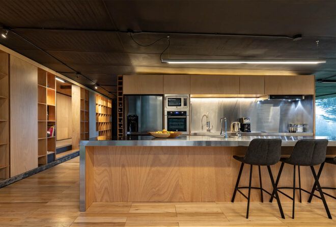 A kitchen with wood walls, floors and cabinets. Countertops and appliances are steel.