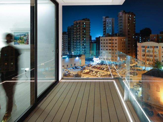 Frosted glass doors lead out onto a balcony that overlooks a city at night.