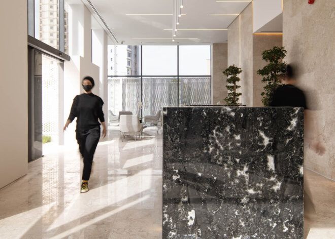 A person walking through a white lobby with a large black marble desk.