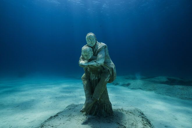 A sculpture of a person giving another person a piggyback ride underwater.
