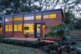 Light filtering out large windows on the tiny home from within at night.