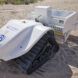 A small white robot with wheels on sand.