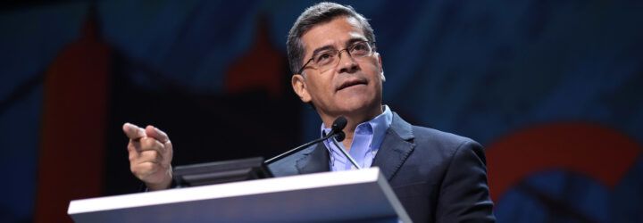 Xavier Becerra standing in front of a podium.