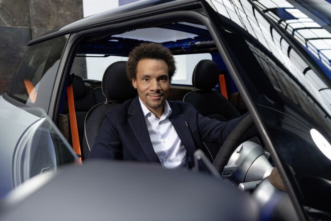 A person sitting in a silver and black car with the door open.